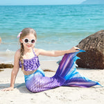 Load image into Gallery viewer, Young girl in a mermaid tail sitting on a beach with ocean in the background
