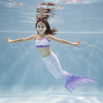 Load image into Gallery viewer, Child in a mermaid tail swims underwater with a clear blue background