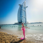 Load image into Gallery viewer, Child in a mermaid tail on a beach with the Burj Al Arab in the background