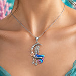 Load image into Gallery viewer, A silver crescent moon and mermaid pendant necklace with blue, pink, and purple enamel detailing, accented with rose gold flowers and dangling silver stars, shown on a plain light gray background.
