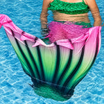 Load image into Gallery viewer, Girl in pool wearing the Pretty Green & Pink Mermaid Tail with added dorsal fins. Reminiscent of a watermelon. Complete with matching, larger, more coverage, frill halter-neck bikini. Part of our luxury range, this tail has a high quality side zip. Mini Mermaid Tails