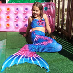 Load image into Gallery viewer, Smiling girl on pool deck wearing the striking Rich Blue & Dark Pink Mermaid Tail with added dorsal fins. Complete with matching material halterneck bikini with cute embellished bow. Part of our luxury range, this tail has a high quality side zip. Mini Mermaid Tails
