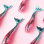 Load image into Gallery viewer, Colourful mermaid tail tube filled with sparkly purple lip gloss Lightly pigmented this lip gloss will leave your lips feeling soft & moisturized. Vegan friendly and cruelty free but not suitable for anyone with a nut allergy. Pink with teal blue mermaid tail tops. Mini Mermaid Tails