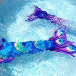 Load image into Gallery viewer, The Peacock feather design Mermaid Tail with added dorsal fins shown in water. Complete with matching material halter-neck bikini with cute embellished bow. Part of our luxury range, this tail has a beautiful peacock feather design and a high quality side zip. Mini Mermaid Tails