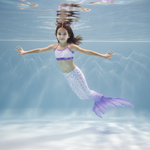 Charger l&#39;image dans la galerie, Child in a mermaid tail swims underwater with a clear blue background
