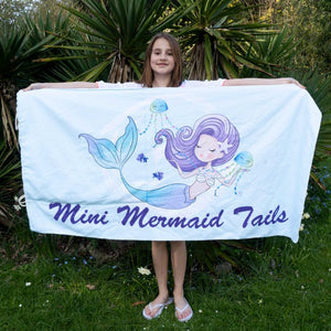 Young girl holding a beach towel that folds up into a bag