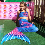 Load image into Gallery viewer, Smiling girl on pool deck wearing the striking Rich Blue &amp; Dark Pink Mermaid Tail with added dorsal fins. Complete with matching material halterneck bikini with cute embellished bow. Part of our luxury range, this tail has a high quality side zip. Mini Mermaid Tails

