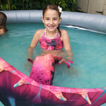 Load image into Gallery viewer, Smiling girl in pool wearing the unusual Pink &amp; Black Mermaid Tail with added dorsal fins. Complete with matching material halter-neck bikini with cute embellished bow.  Part of our luxury range, this tail has a high quality side zip. Mini Mermaid Tails
