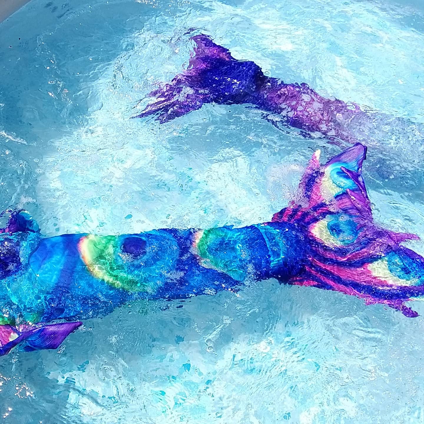 The Peacock feather design Mermaid Tail with added dorsal fins shown in water. Complete with matching material halter-neck bikini with cute embellished bow. Part of our luxury range, this tail has a beautiful peacock feather design and a high quality side zip. Mini Mermaid Tails
