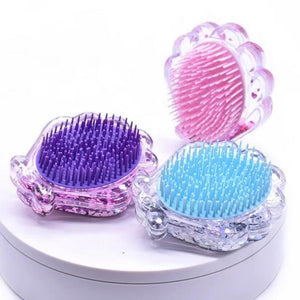 Photo shows the hairbrush side of the sparkly glitter seashell detangling hairbrushes in pink, purple, and blue. Gold also available. Mini Mermaid Tails