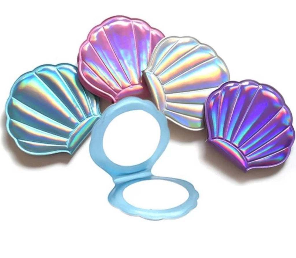 Pretty Shimmery Hologram Sea Shell Mermaid Compact Hand Mirror with one regular and one magnifying side.  Folding make up mirror made from PU leather.  Available in Purple, Blue, Pink & White. Mini Mermaid Tails